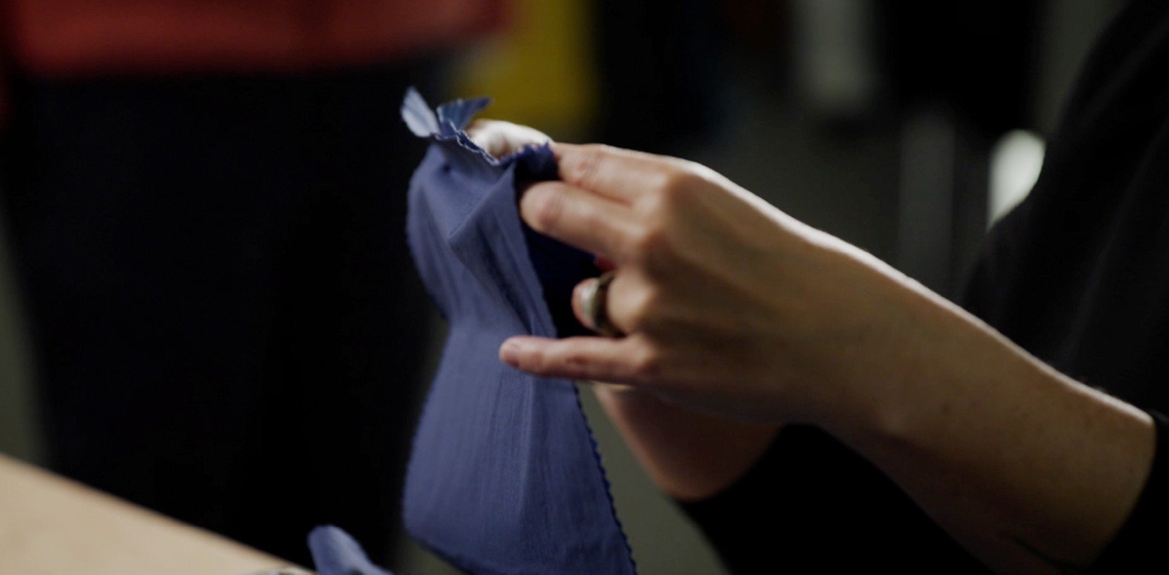 A pair of hands stretches out the a sample of fabric that makes up the Wind Challenger jacket