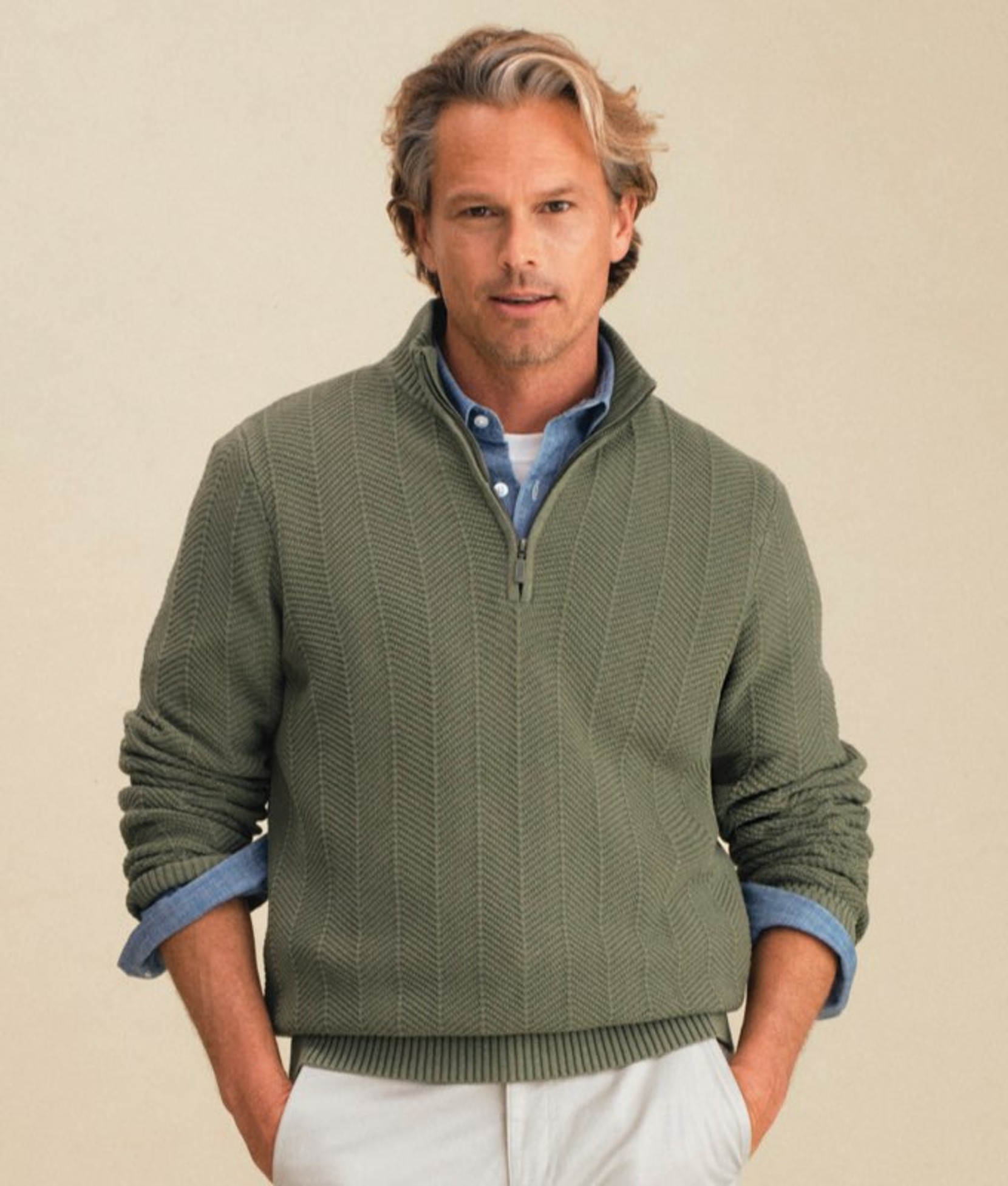 Man wearing a green sweater vest over a plaid button-down shirt.