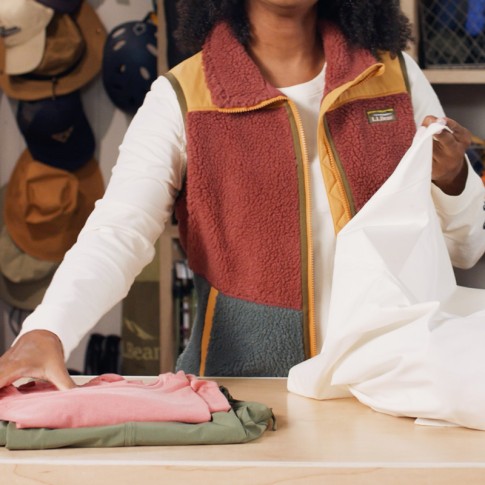 Stephanie beginning to stuff a pillowcase with clothing to use as a pillow.