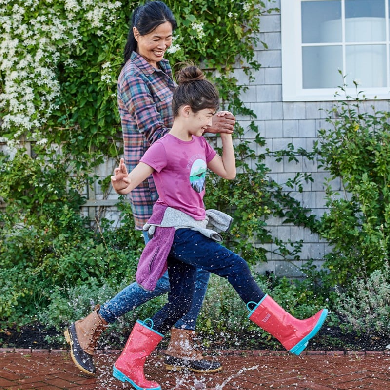 Mother and daughter stomp in rain puddles.