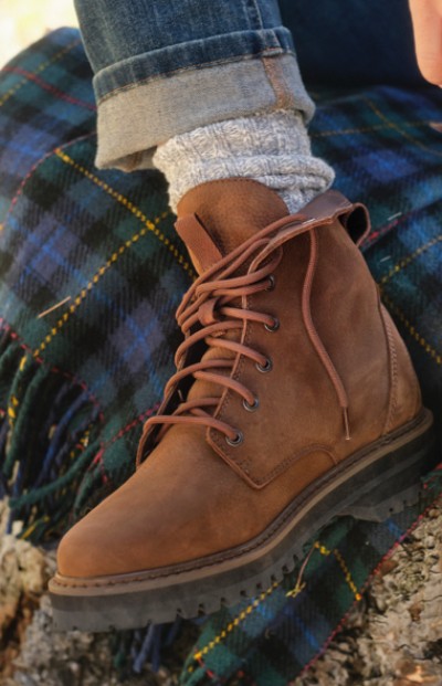 A close up of a brown boot on a tartan blanket, highlighting textures and casual style. 