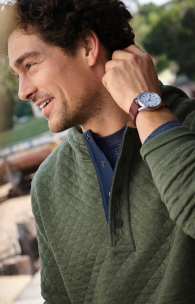 Close up of a person in a green quilted pullover standing outdoors near a vehicle.