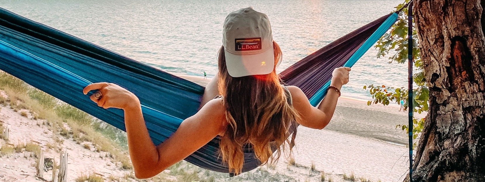 A woman sitting in a hammock overlooking the beach.