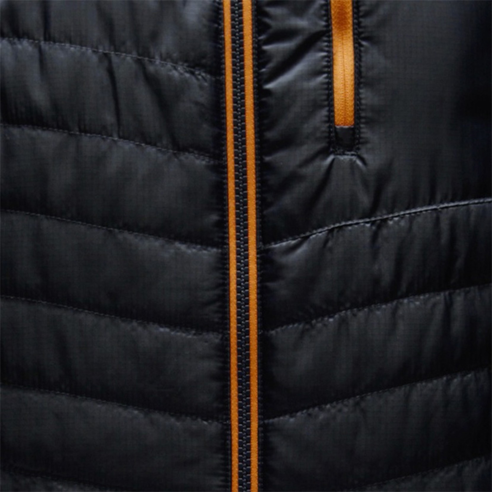 Close-up of black puffer jacket with orange zipper and pocket trim.