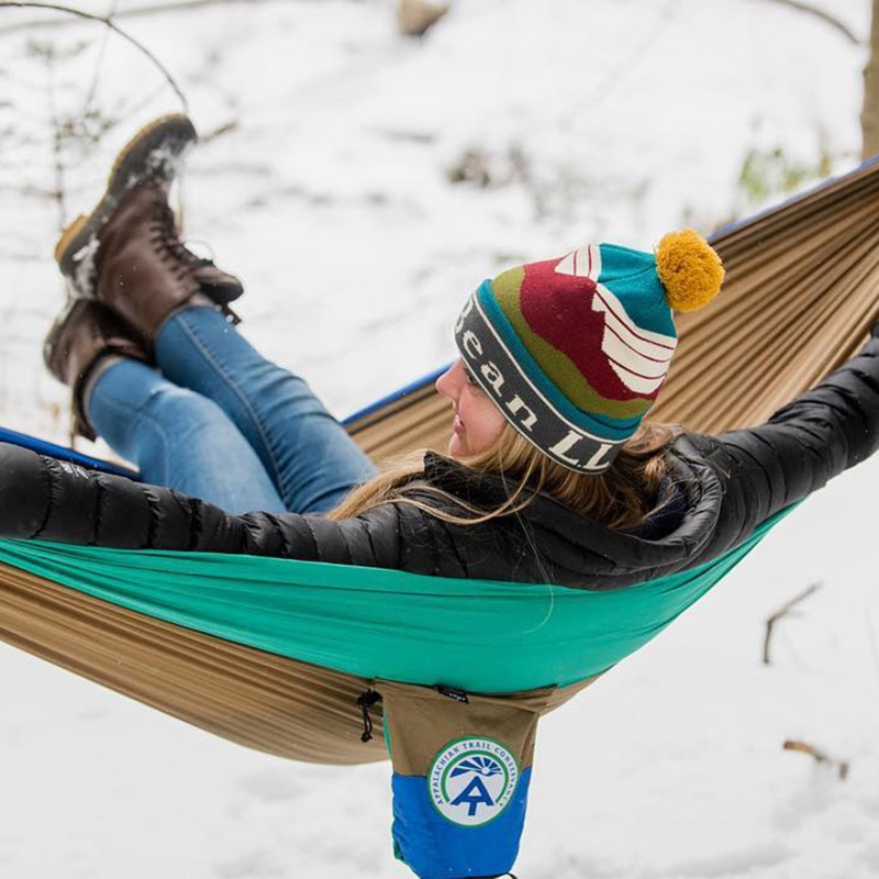 A woman lying in a hammock on a winter day.