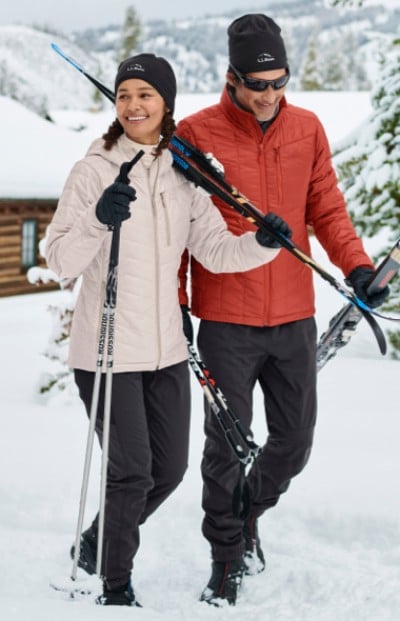 People walking in the snow with skiing gear.