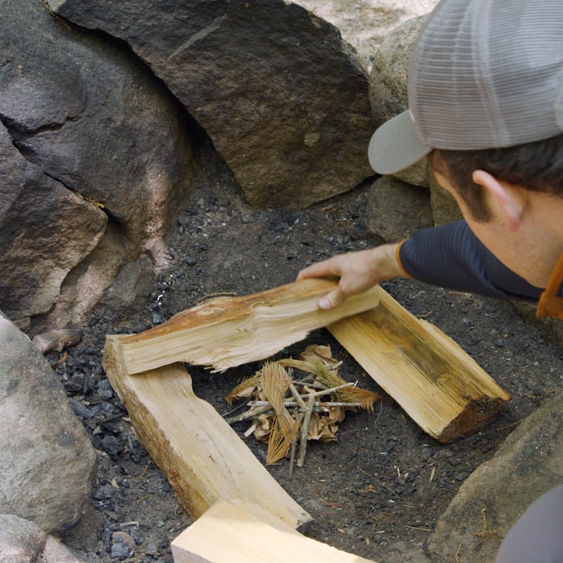 A pile of small twigs, pine needles and dry leaves in the center of a fire ring.