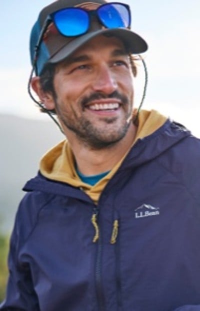 A man wearing a blue jacket with an L L Bean logo, a yellow hoodie underneath.
