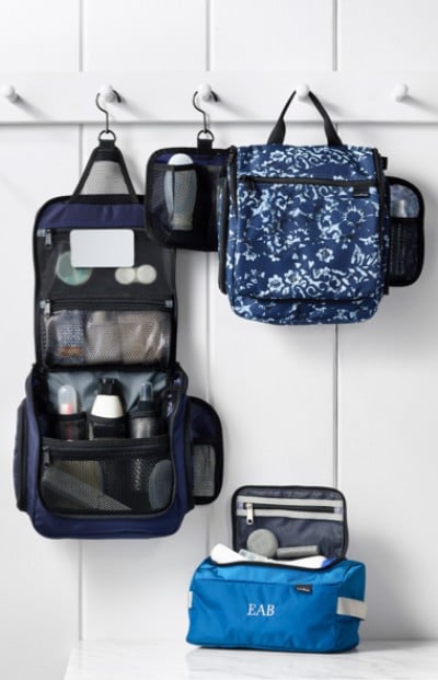 Three hanging toiletry bags on hooks against a white wall, showcasing organized storage solutions.