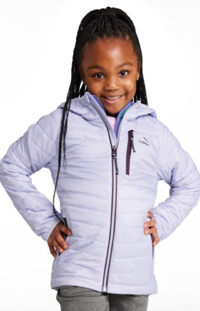 Smiling child wearing a light purple jacket stands with hands on hips.