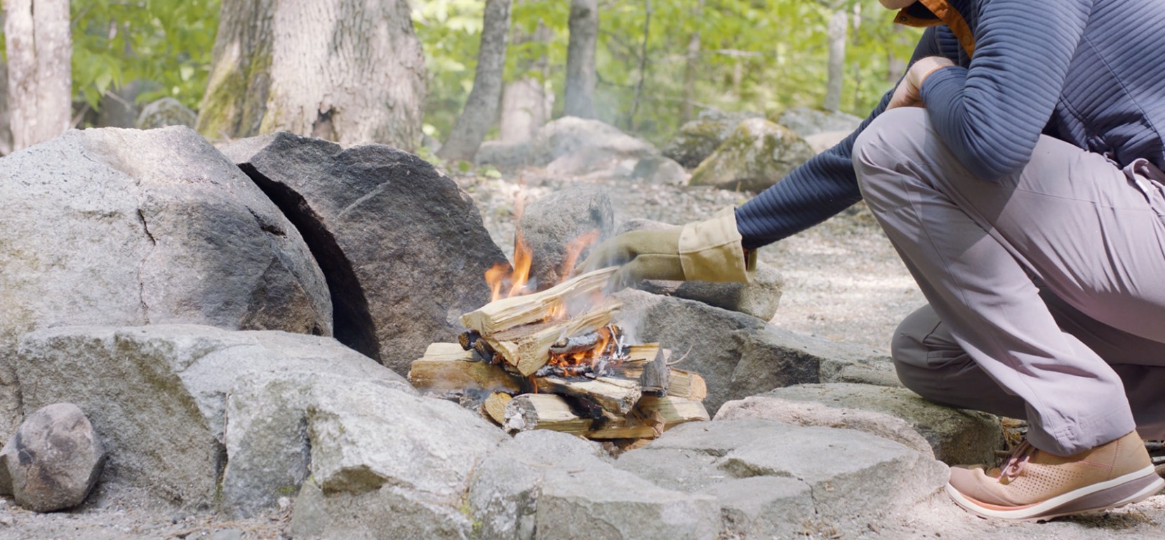 Nate adding a log to the fire wearing a heat proof glove.