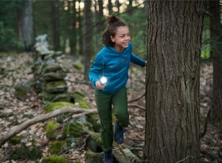 A young girl in an L.L. Bean sweatshirt with a flashlight playing flashlight tag