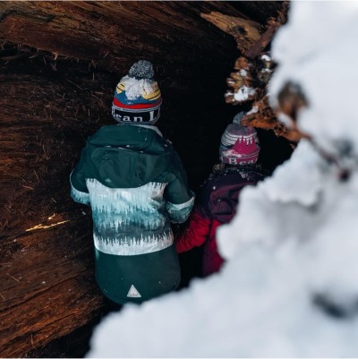 2 kids wearing L.L.Bean outerwear and pom hats outside in the snow.