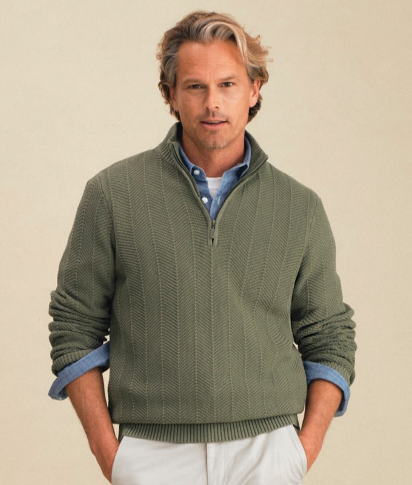 Green men’s pullover worn by a model with hands in pockets. 