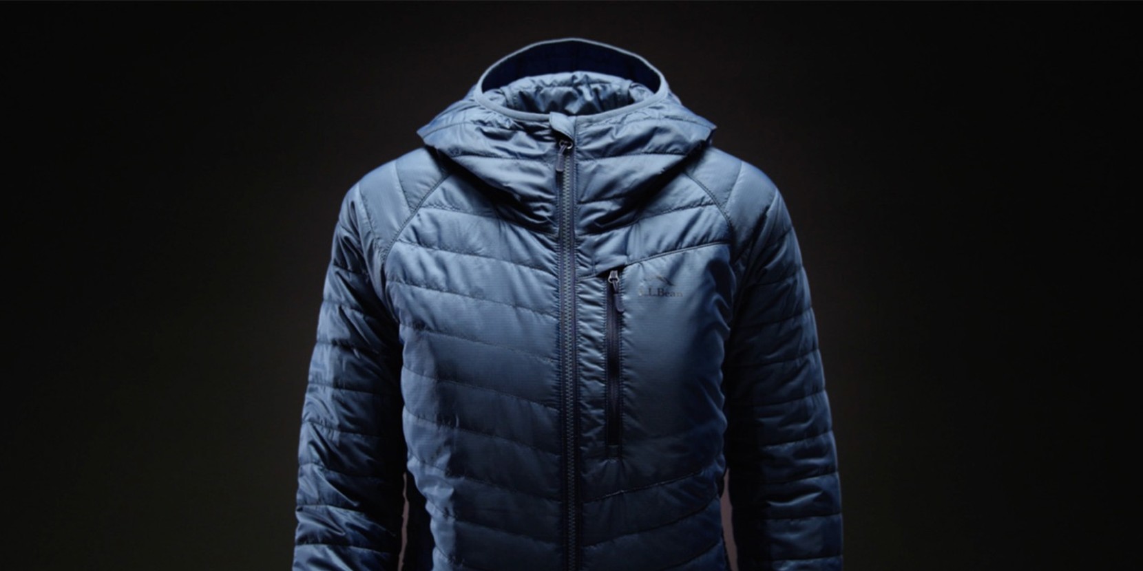Blue L L Bean puffer jacket with hood shown against a dark background.
