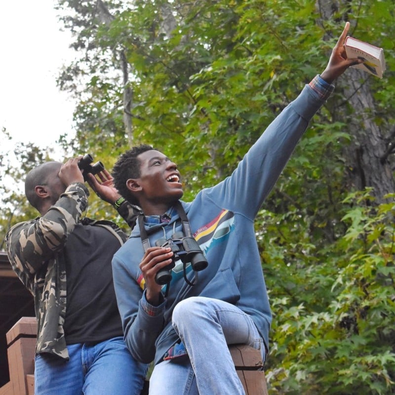 Isaiah Scott holding binoculars and pointing.