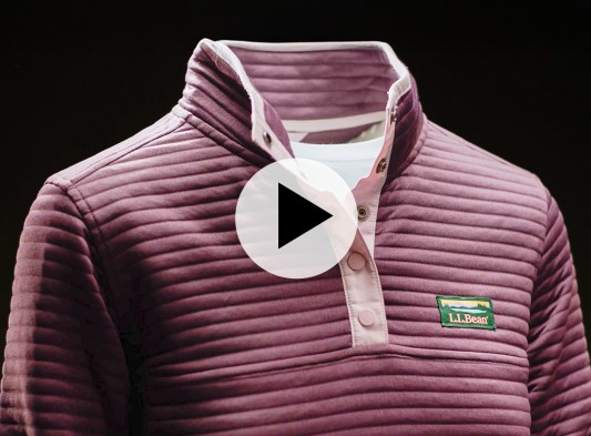 Plum-colored ribbed pullover with a snap-button collar and L L Bean logo, shown on a mannequin against black background with play video icon.