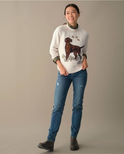 Woman standing wearing a Signature Original Cotton Sweater, a motif of a dog on the front.