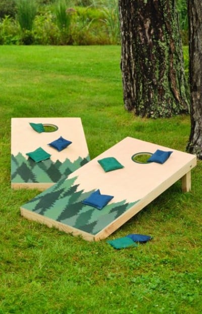 Image of two cornhole boards with beanbags all sitting on green grass.