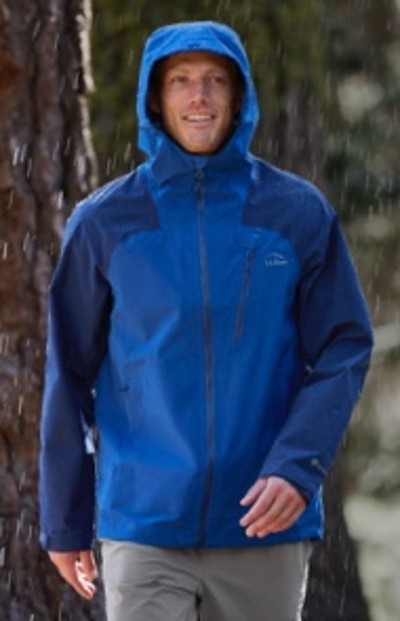 A person in a hooded rain jacket stands outdoors.