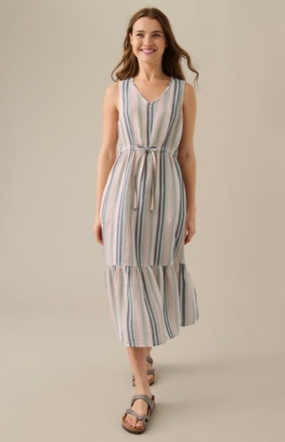 A woman wearing a sleeveless, striped dress with vertical pastel stripes and a tie at the waist.