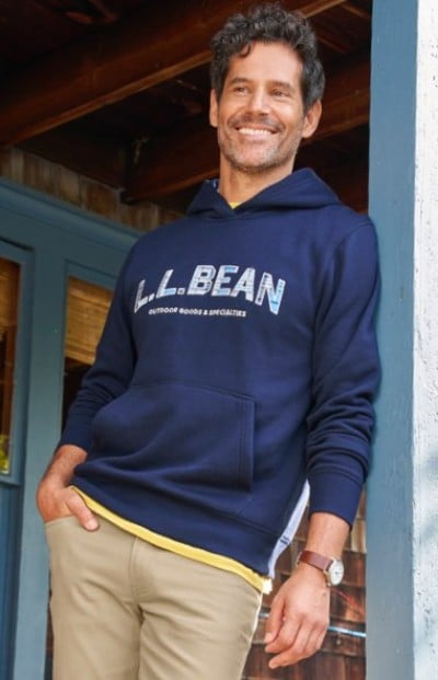 Person wearing a navy L. L. Bean hoodie and tan pants, standing casually near a wooden doorway.