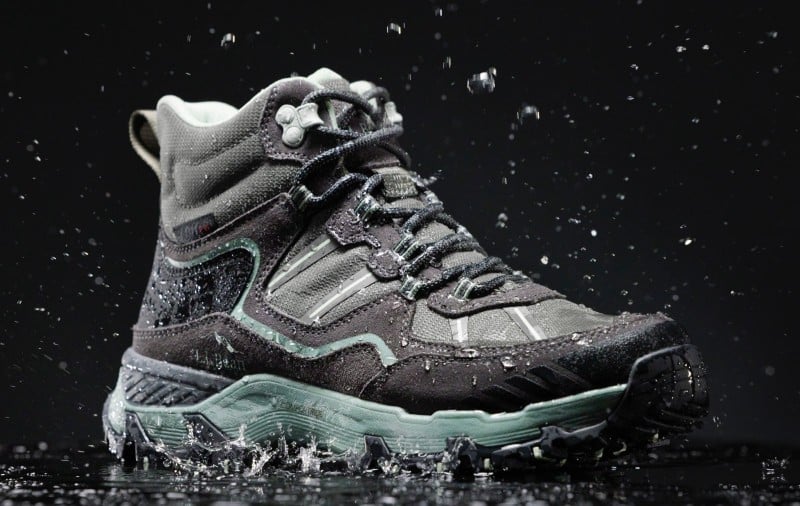 Hiking boot splashing in water against a dark background. 