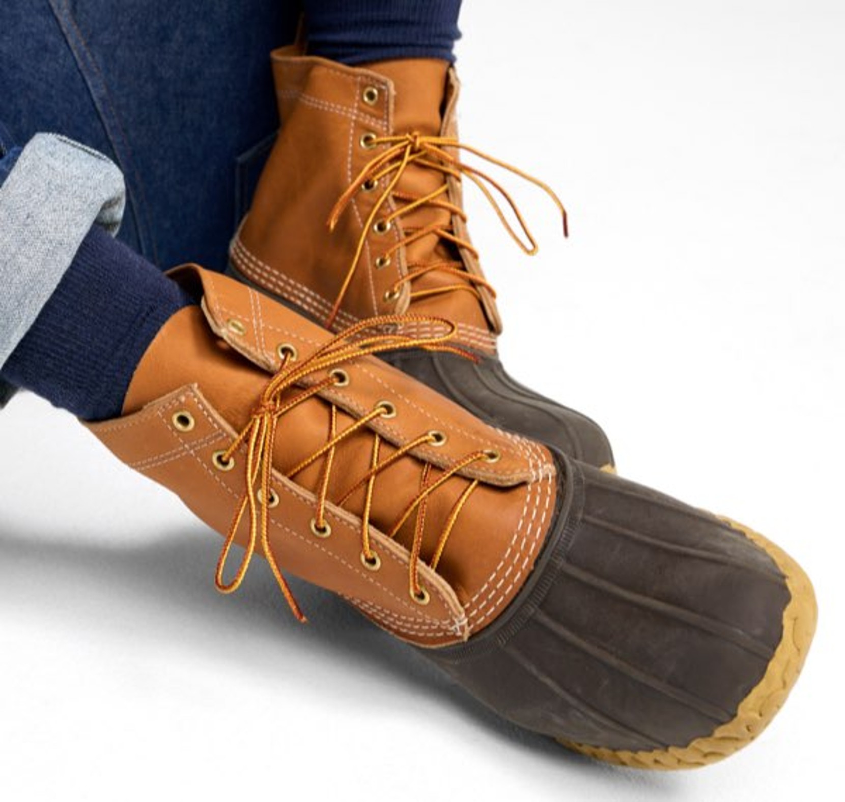 Person wearing tan lace-up rain boots with dark rubber soles. 