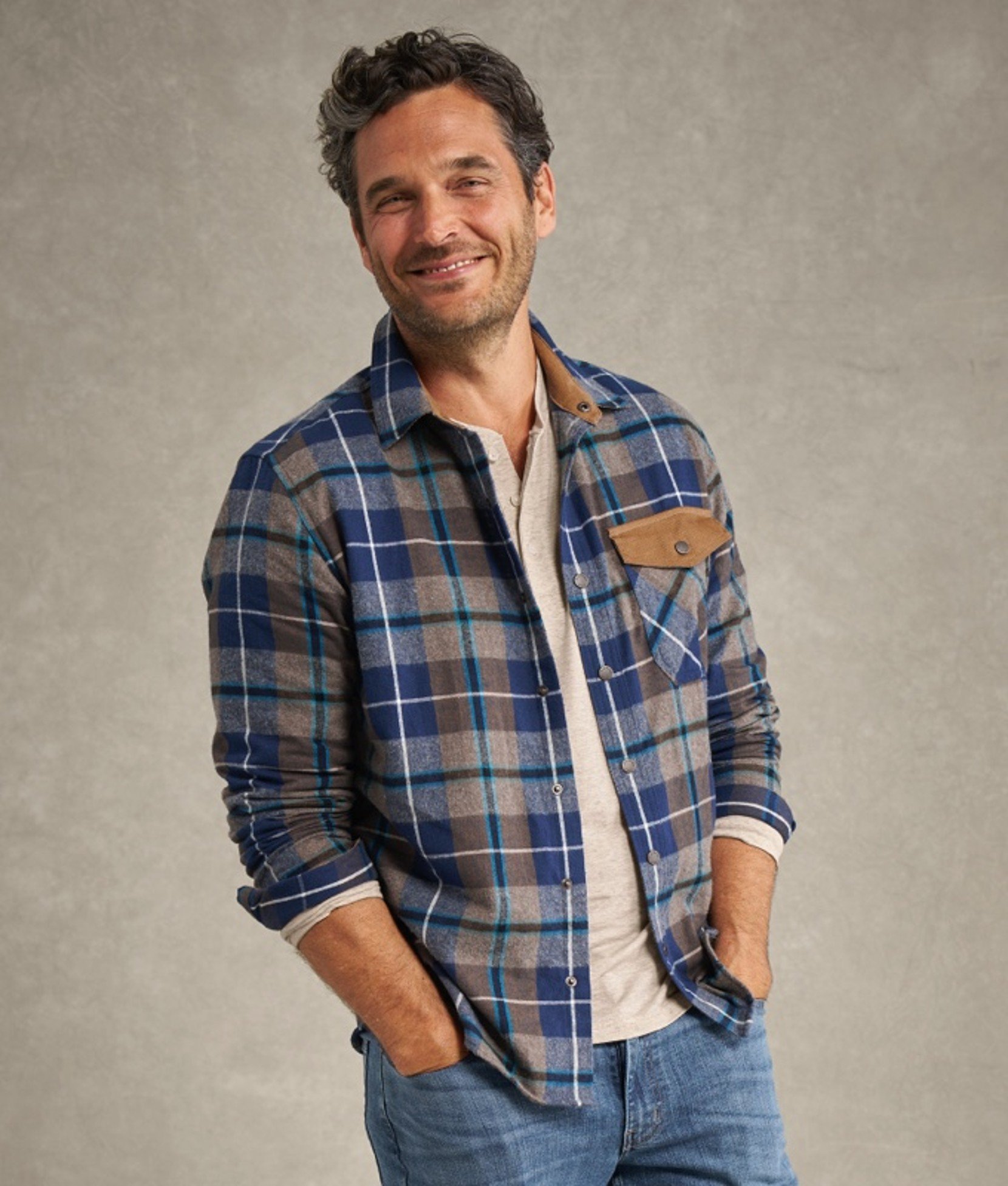 Man in blue and green plaid flannel shirt with hands in pockets.