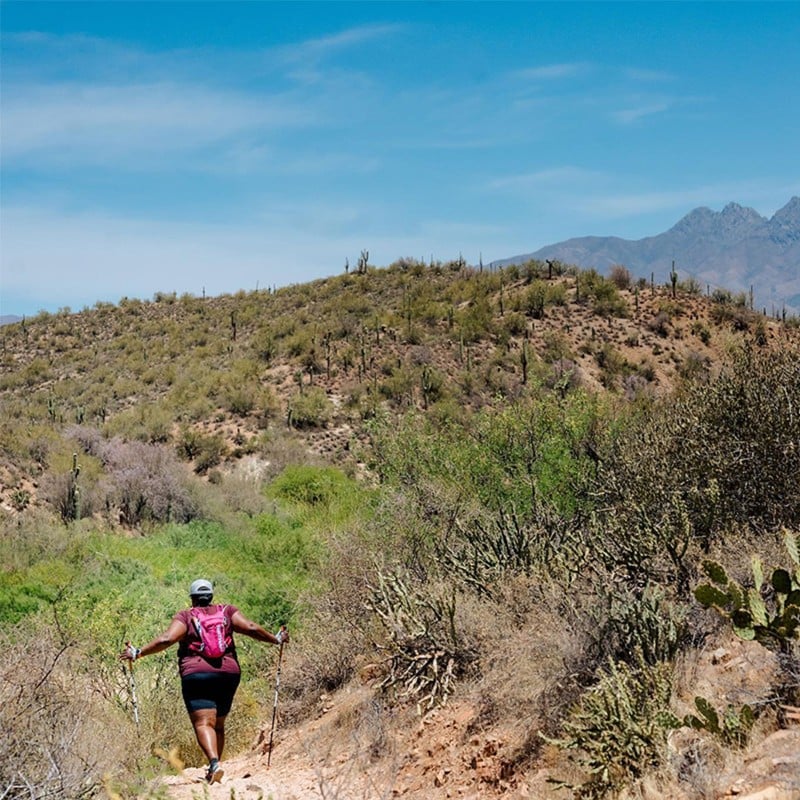 L.L.Bean Ambassador Mirna Valerio walking on a high desert trail, mountains in the distance.