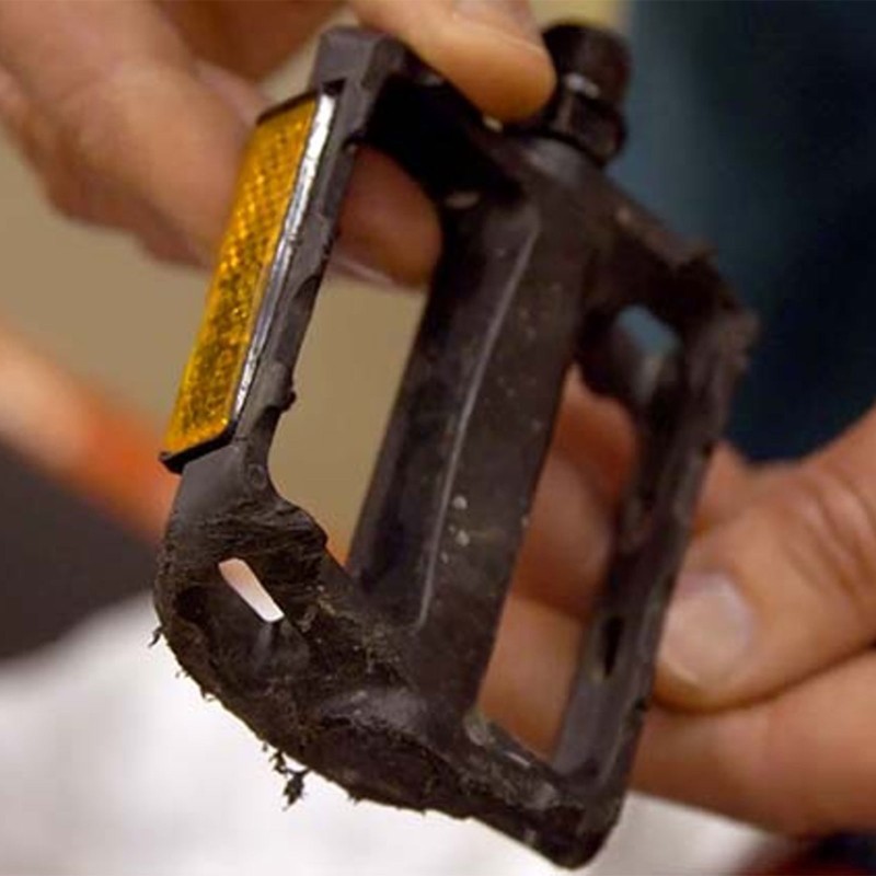 Close-up of 2 hands holding a bicycle pedal.