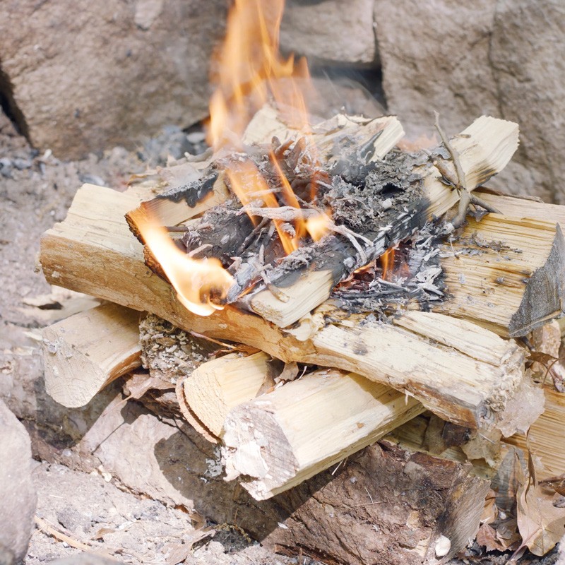 Nate adding tinder to the first layer of logs, filling the gaps between logs.