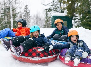 Happy children with helmets sledding in Sonic Snow Tubes.