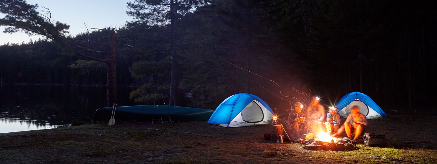 Family gathered around a campfire at night.