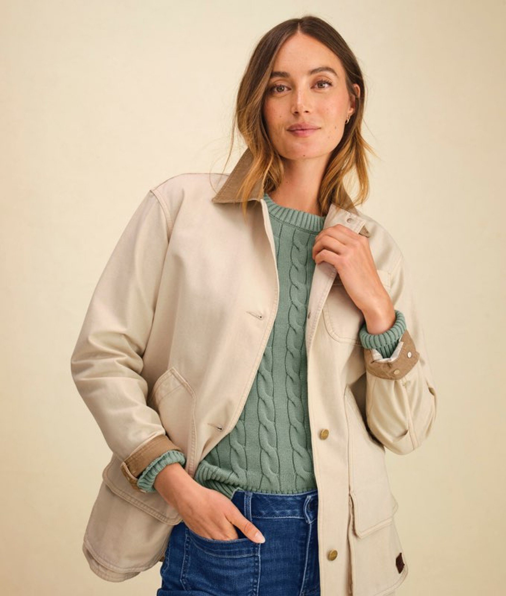 Cream women’s cardigan worn over a green top by a model. 