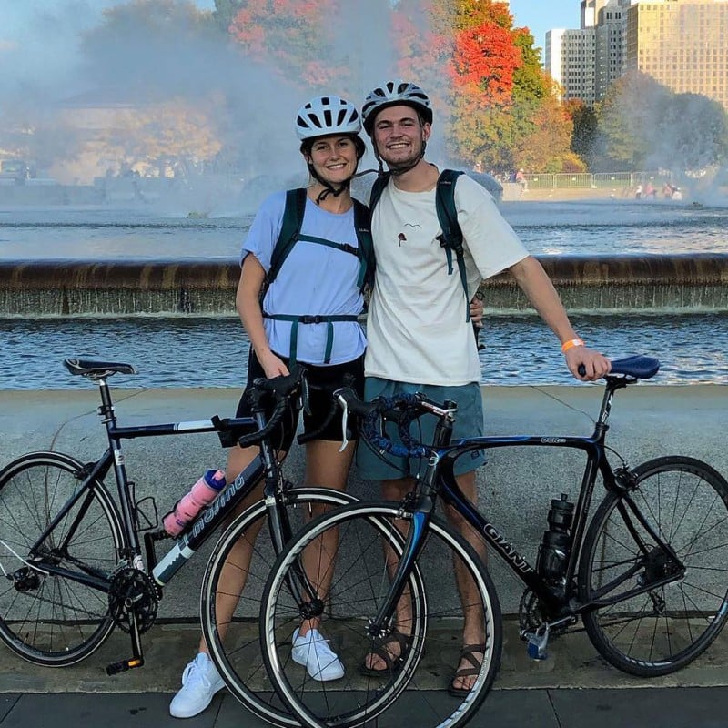 A couple standing with their bicycles in front of a fountain.