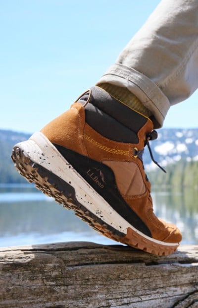 A close up of a hiking boot on a log by a lake, highlighting an outdoor lifestyle and a moment of connection with nature.