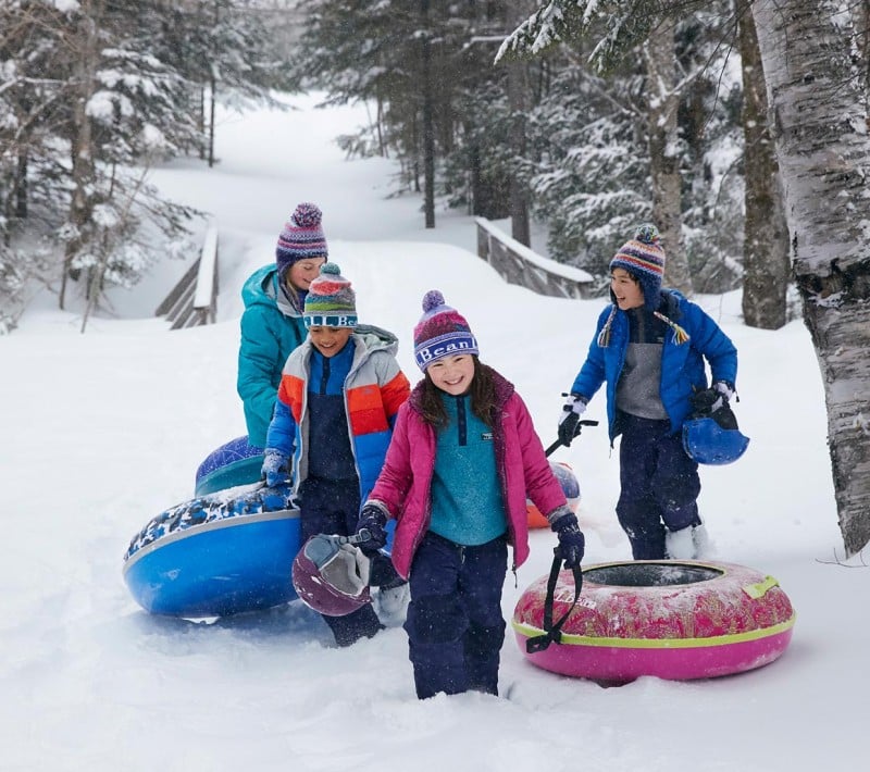 4 kids climbing a sledding hill.