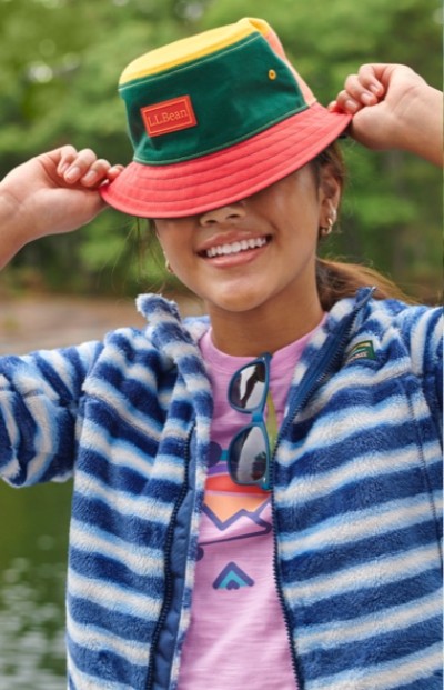 Smiling child holding bucket hat outside.