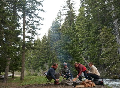 Friends outside sitting around a campfire.