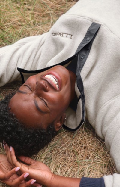 A woman wearing a fleece quarter zip top lies in the grass.