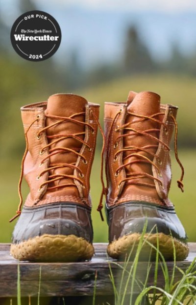 L. L. Bean Boots set on a wooden surface in a grassy, scenic landscape and labeled as Wirecutter’s 2024 pick.