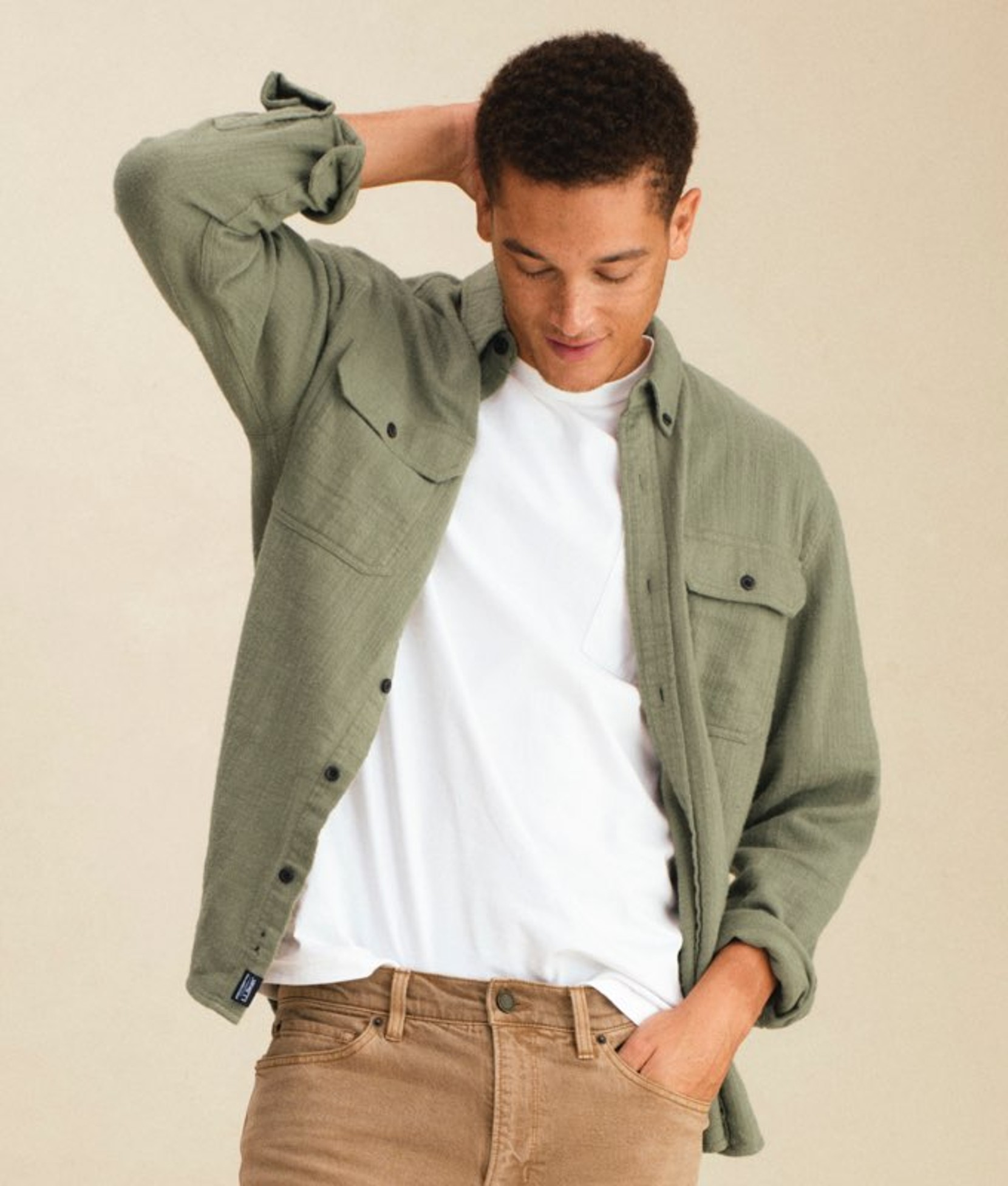 Man standing wearing a green plaid flannel shirt over a white tee.