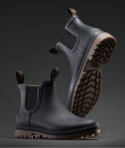 Black L L Bean Wellie boots with brown pull tabs and rugged soles, one upright and one tilted to show tread pattern.