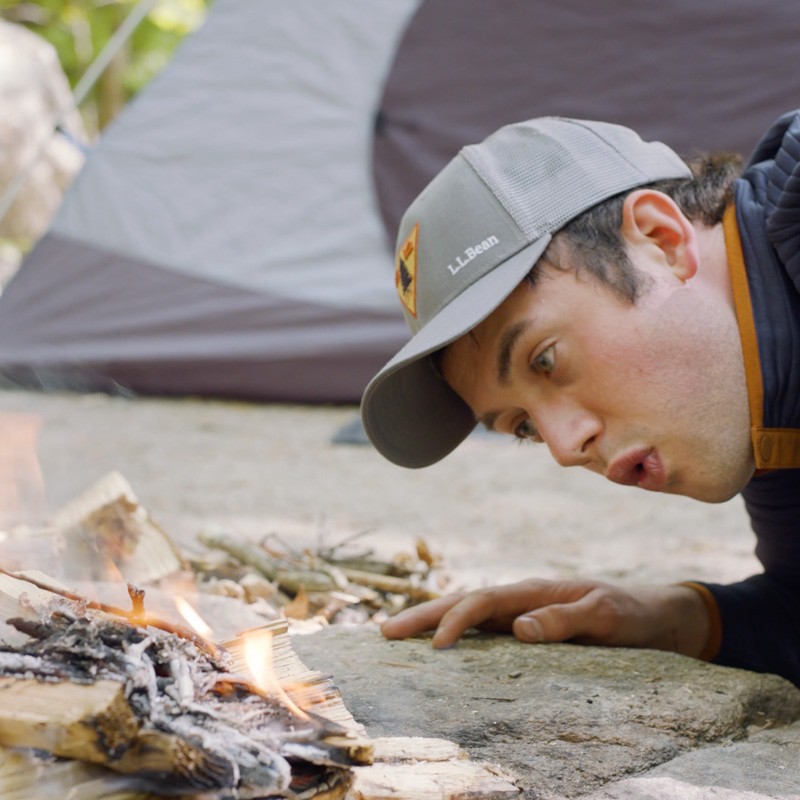 Nate placing a fuel log on either side of a pile of tinder.