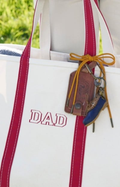 Close up image of a tote bag with monogram sewn on the front and gift tag.