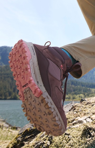 A close up of a shoe with a rugged sole against a backdrop of a serene lake, capturing a moment of outdoor adventure.