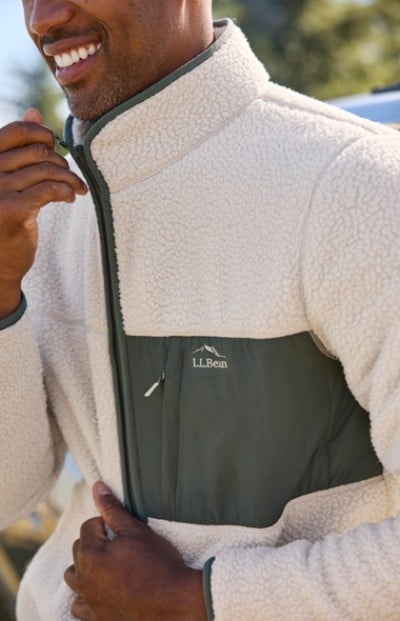 A man is zipping up a white L L Bean fleece jacket.