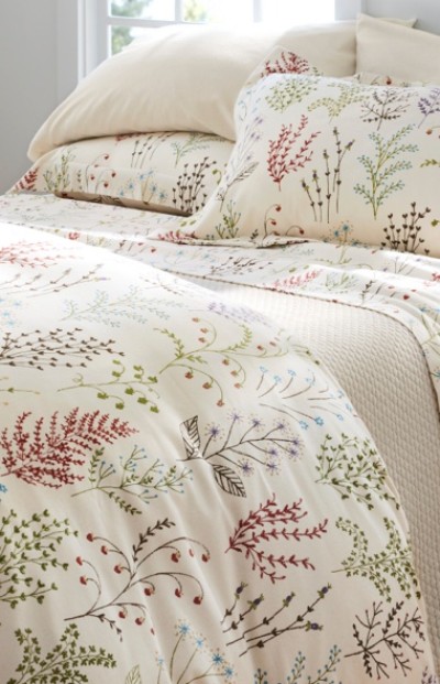 A neatly folded bed with matching floral bedding and pillows.