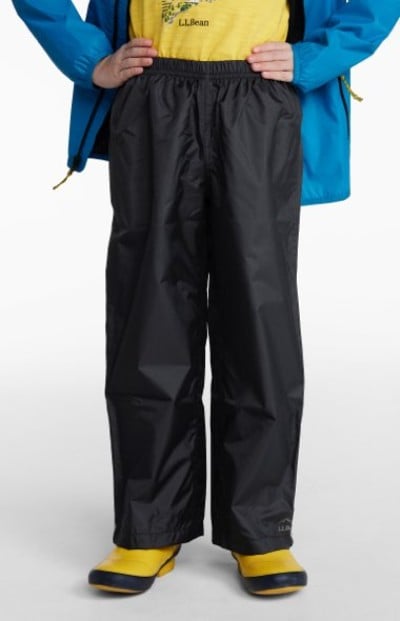 Child wearing black waterproof pants, yellow boots, a yellow shirt, and a blue jacket, shown from waist down.